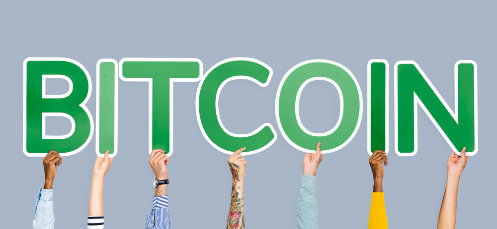 hands holding up green letters forming word bitcoin